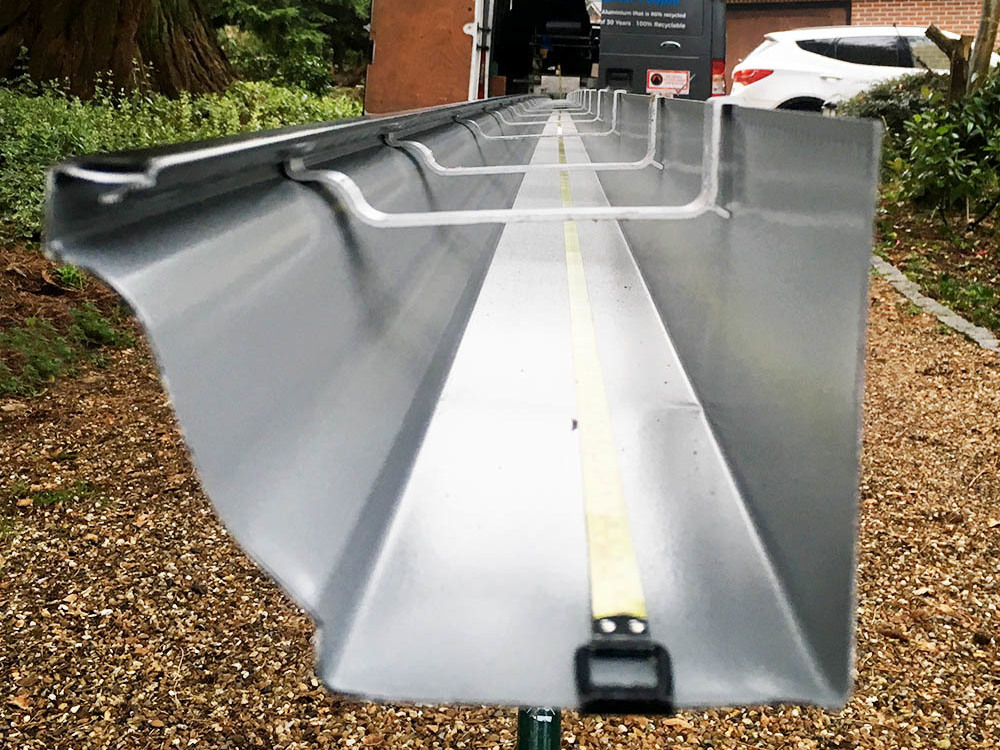 Cross-section of ogee guttering being extruded from specialist machinery on-site.