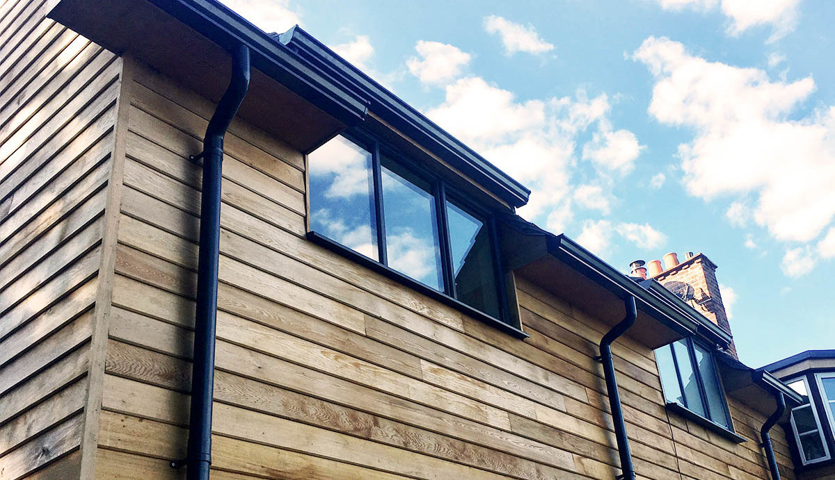 Stylish black aluminium guttering on a wooden-clad domestic property.