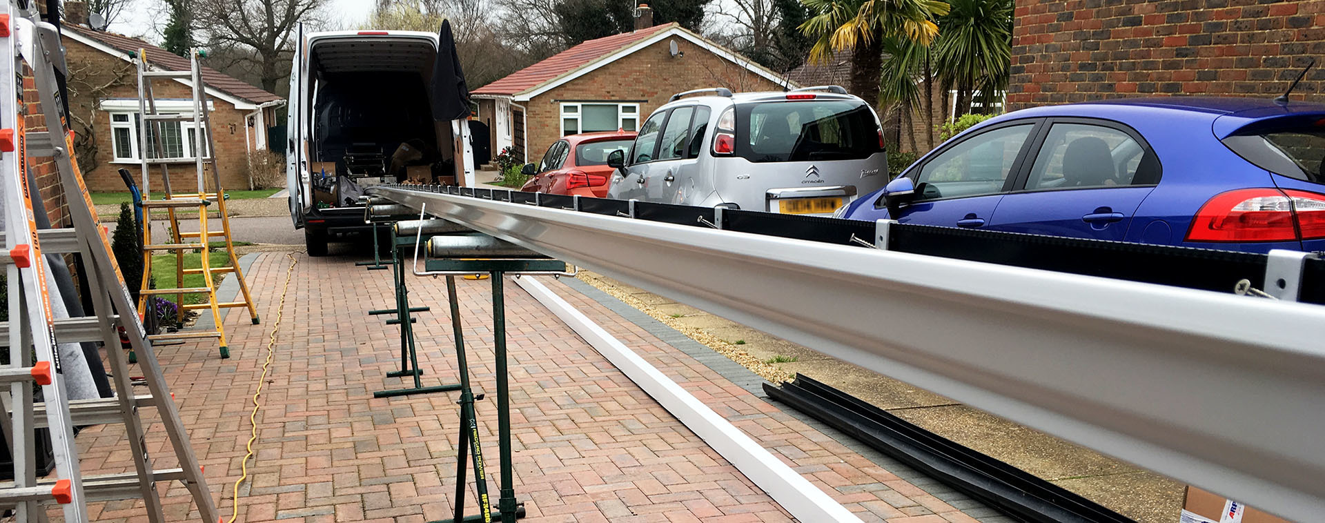 Long, continuous length of ogee aluminium guttering being extruded on-site at a domestic property.